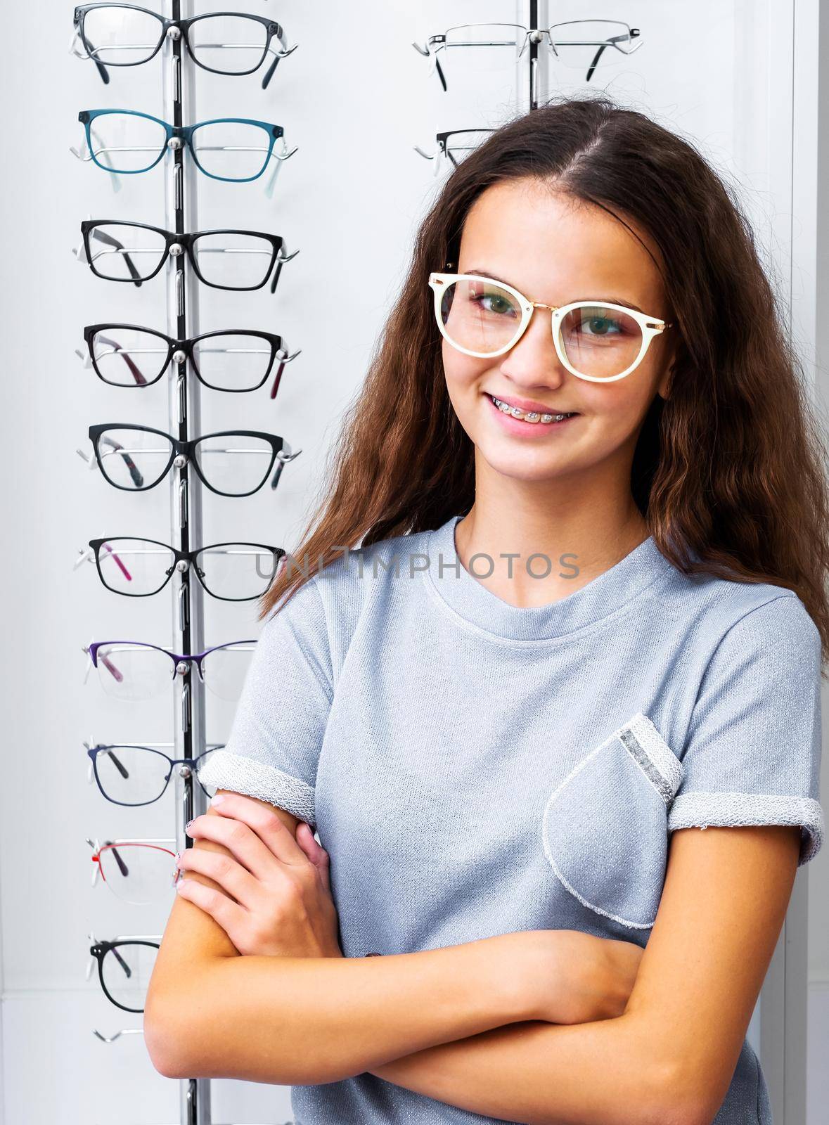 Smiling teenage girl with pretty white glasses standing in the optical store