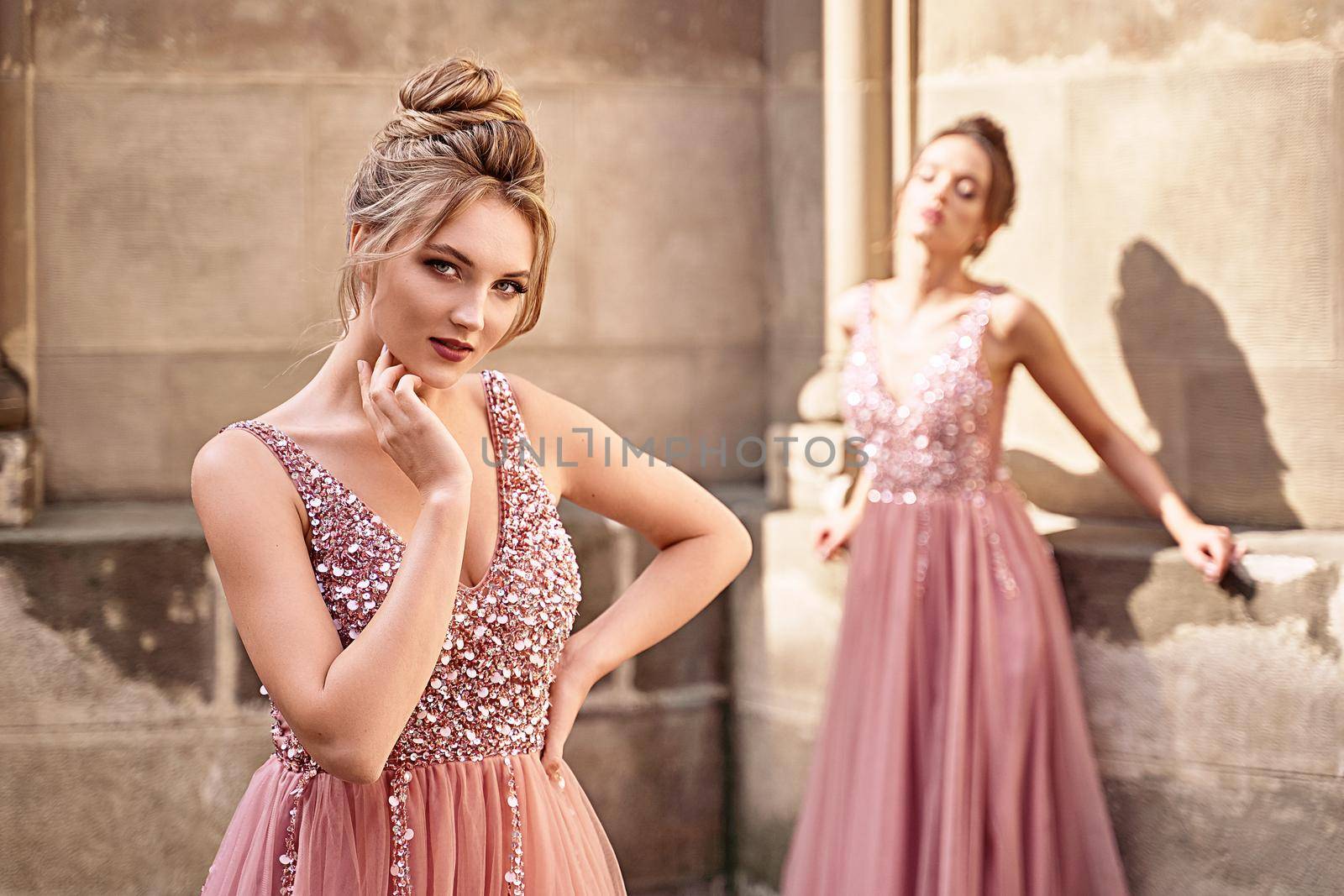 Beautiful bridesmaids in gorgeous elegant stylish red pink violet floor length v neck chiffon gown dress decorated with sequins sparkles and rhinestones holding flowers bouquets. Wedding day in old beautiful European city.