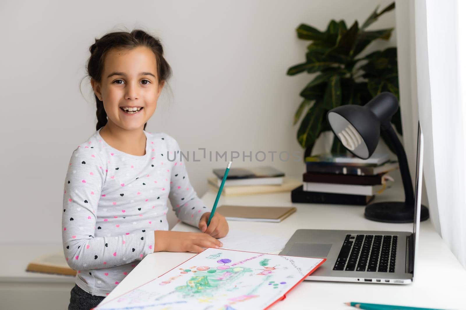 Happy little girl at home working with a laptop