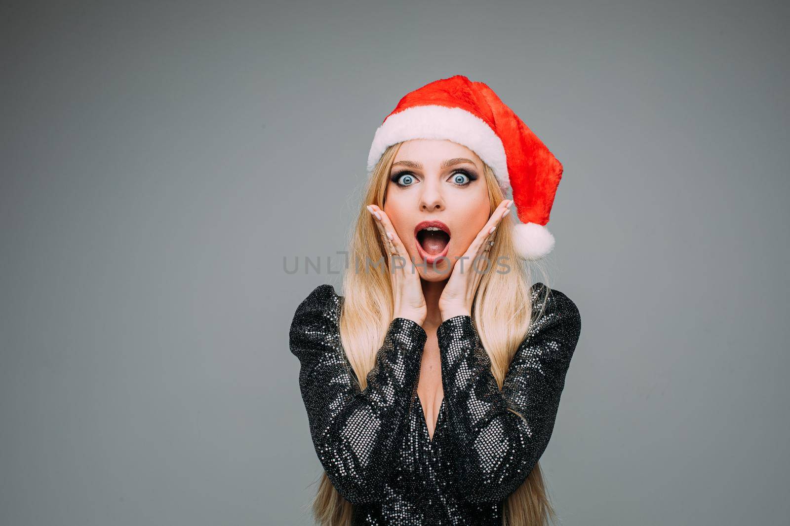 Portrait of pretty surprised lady in black dress posing in studio, isolated on grey background. Happy New Year concept