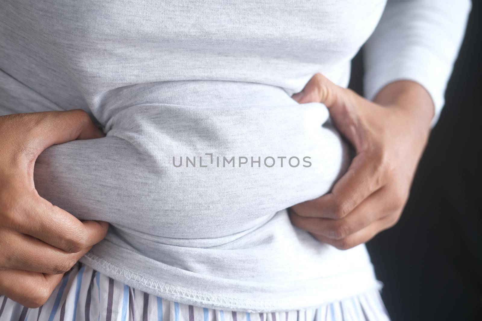 man's hand holding excessive belly fat, overweight concept.