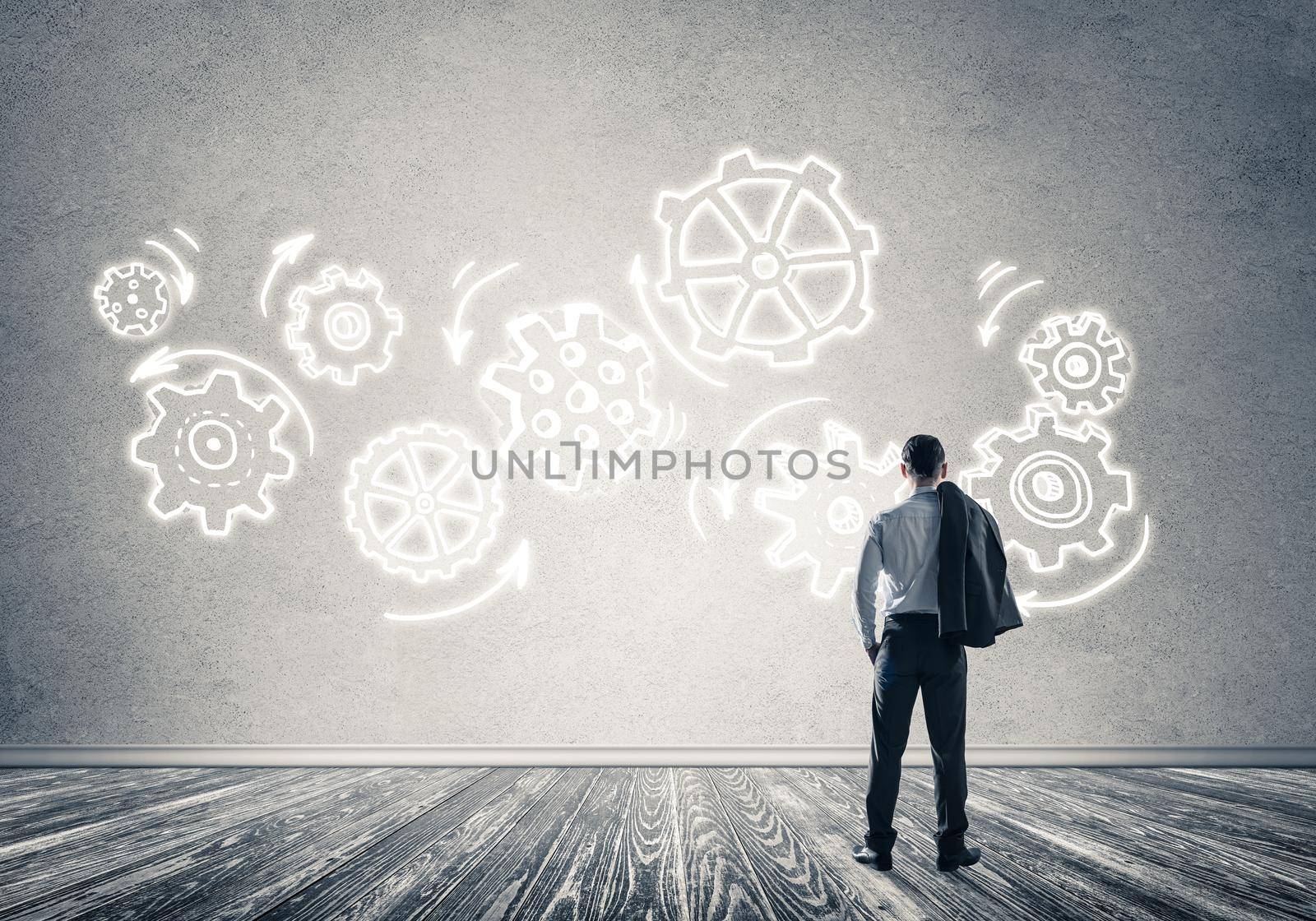 Back view of businessman looking at wall with drawn gear mechanism