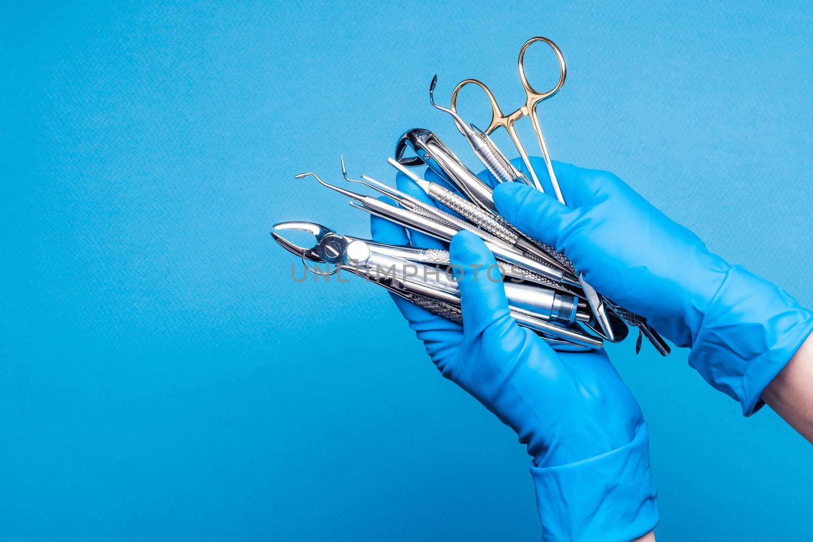 Hands in blue gloves holding dental equipment and metal instruments by GekaSkr