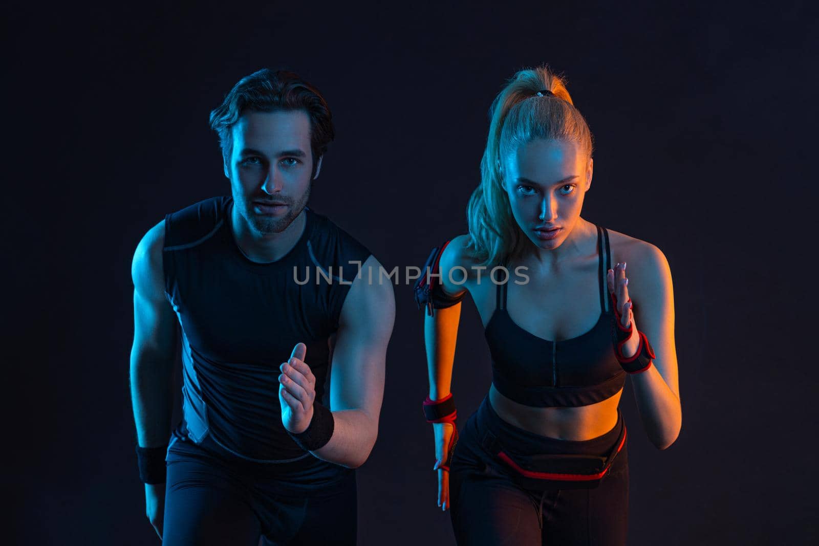 Sprinter run. Strong athletic woman and man running on black background wearing in the sportswear. Fitness and sport motivation. Runner concept. by MikeOrlov