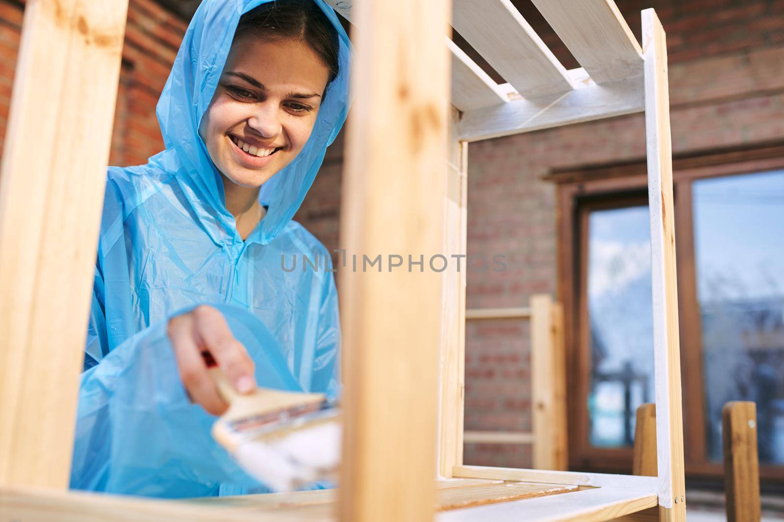 cheerful woman with a paint brush to paint wooden fittings. High quality photo