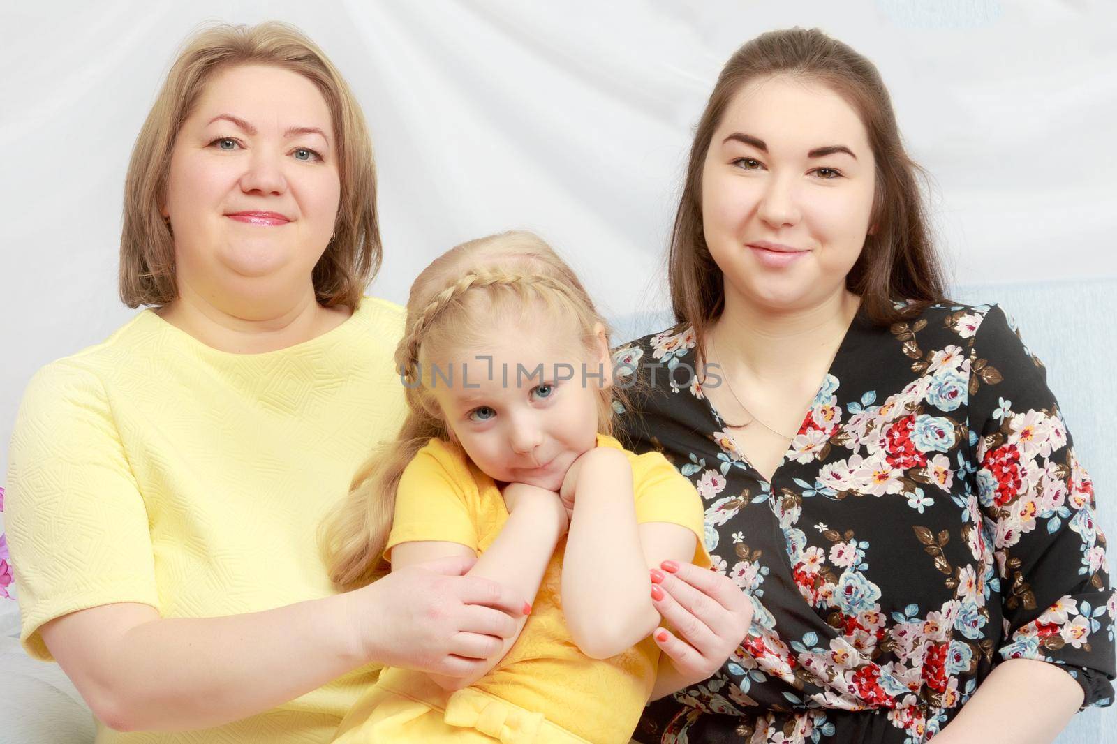 A happy mother hugs her beloved daughters. Senior and younger. Studio photo.