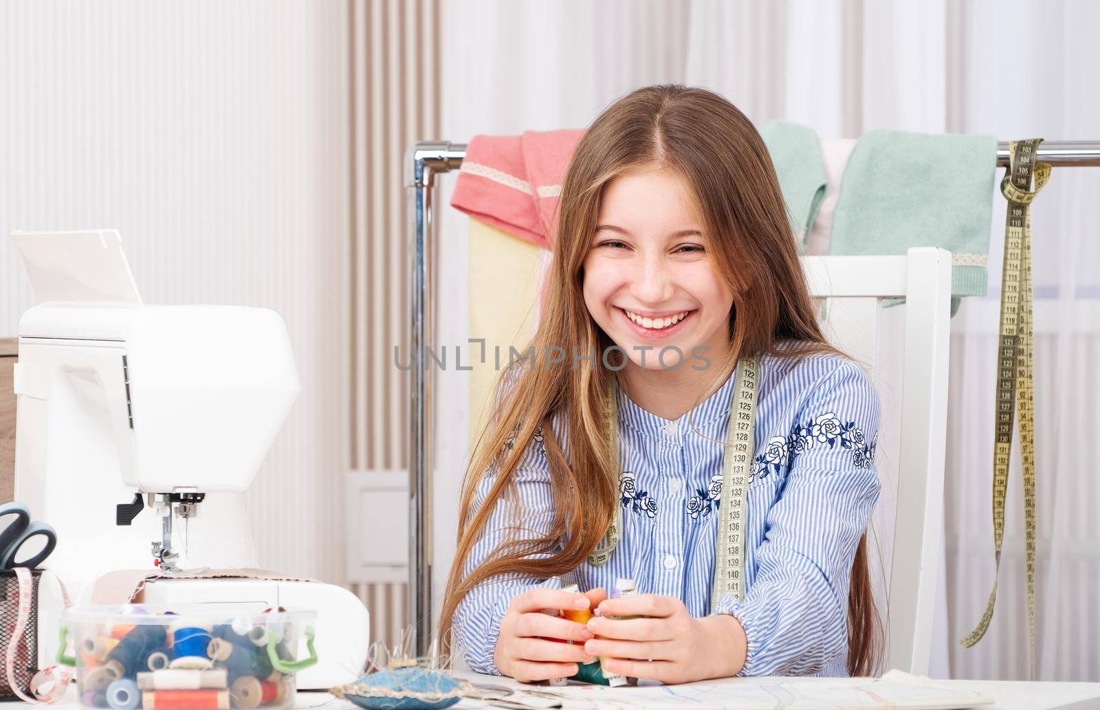 Beatiful teenage girl in popular tailor workshop. holding threads