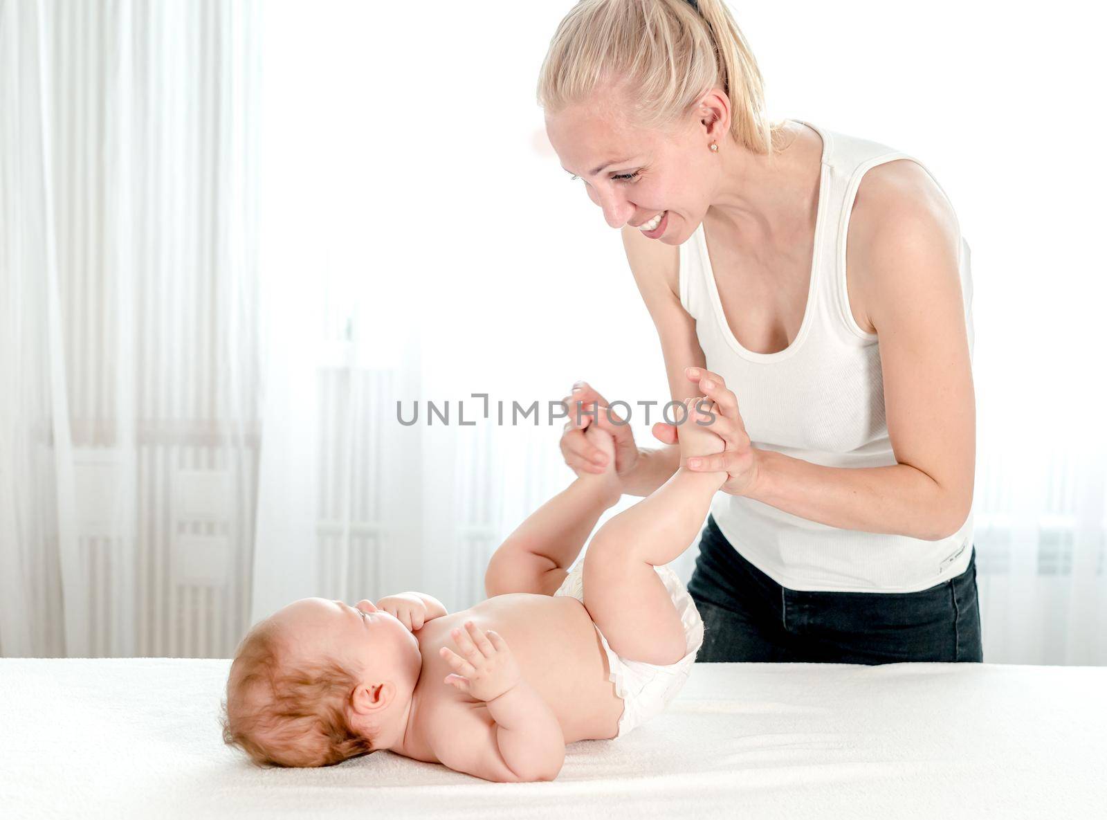 Mother massaging her infant baby by tan4ikk1