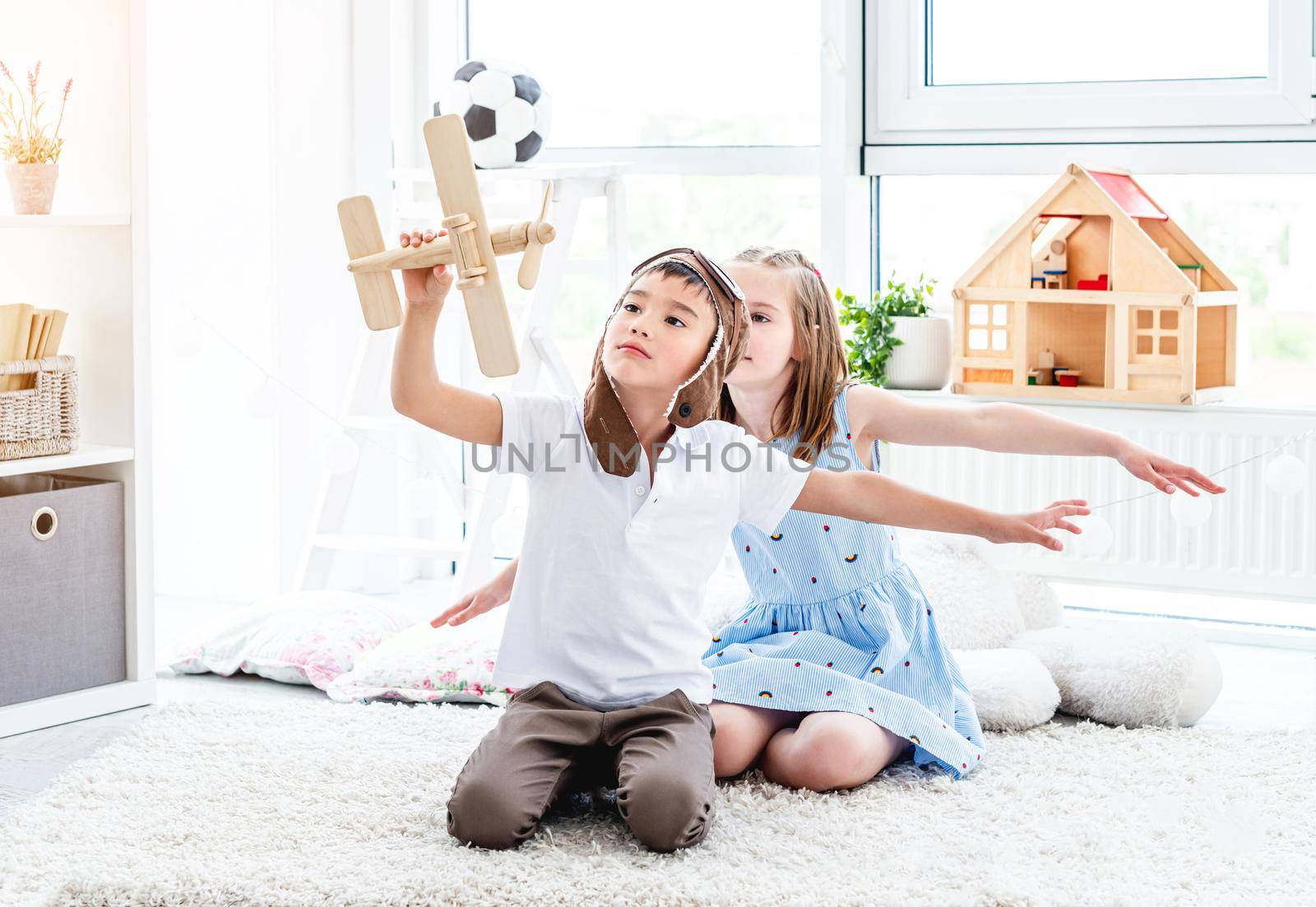 Happy kids playing with plane model sitting in light room