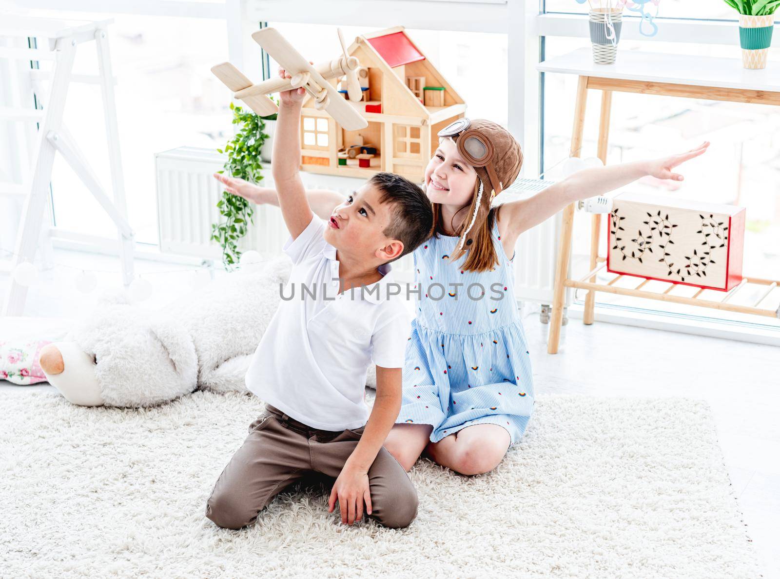 Smiling little friends flying wooden plane in children's room