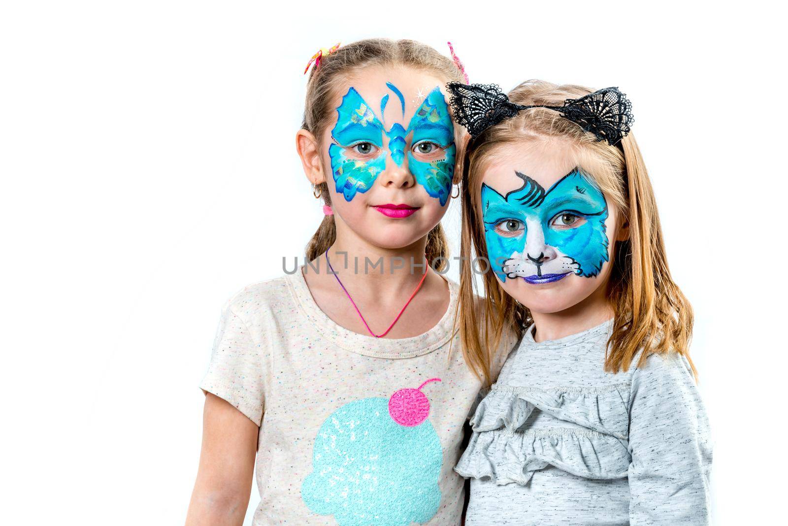 Portrait of two cute girls with face painting of a tiger and butterfly isolated on white background. Little girls with face art paintings for a birthday party