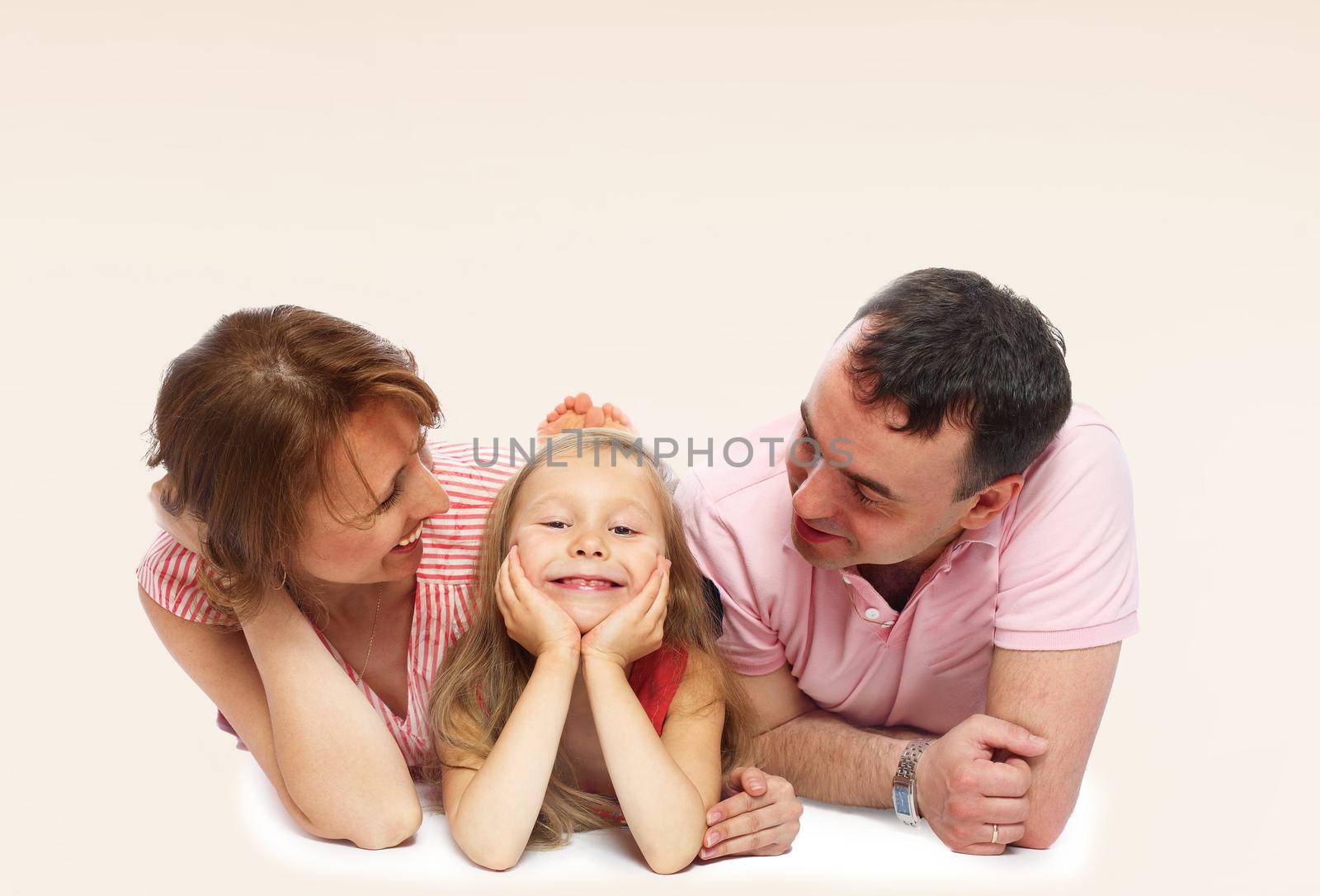 Family of three mom dad and daughter lying on the floor.