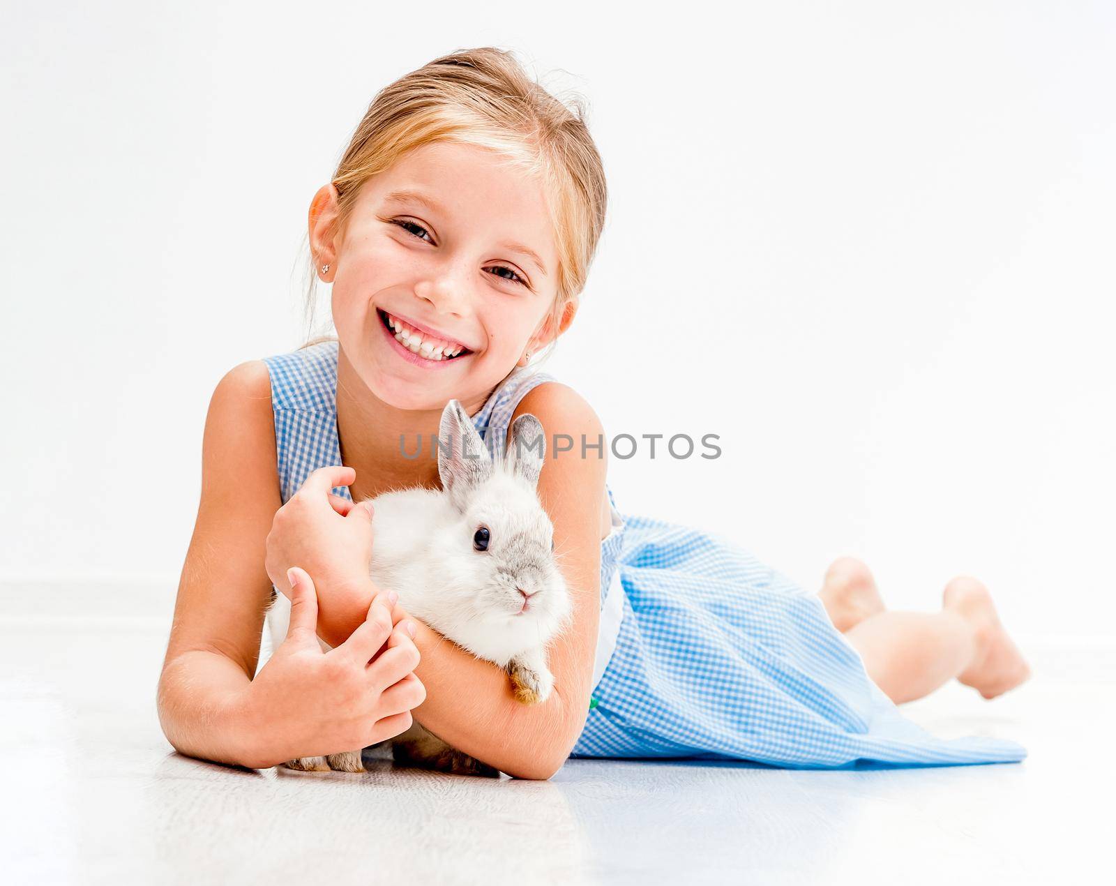 cute smiling girl in a blue dress with a white rabbit