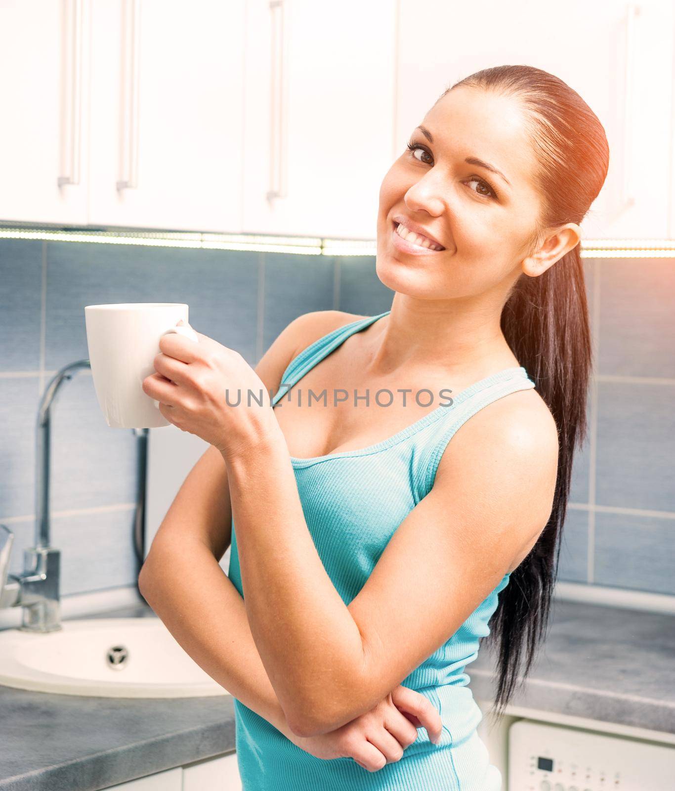 young beautiful girl drinking tea from a mug at home in the kitchen