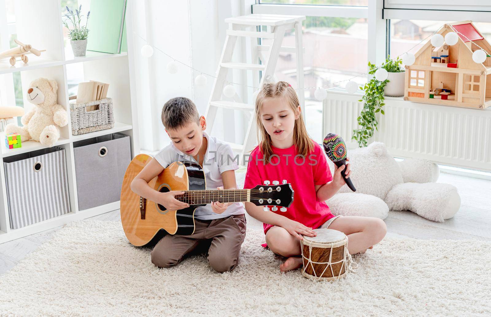 Smiling kids playing on drum and guitar in modern apartment