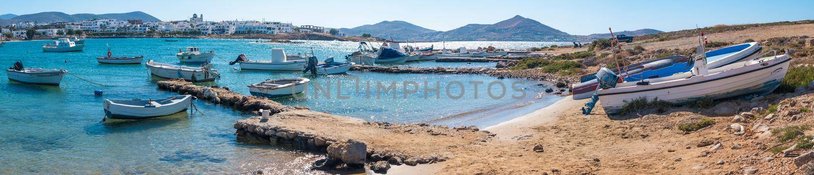 Panoramic view of small fishing boats moored at quiet small stone quay and motorboats on the shore