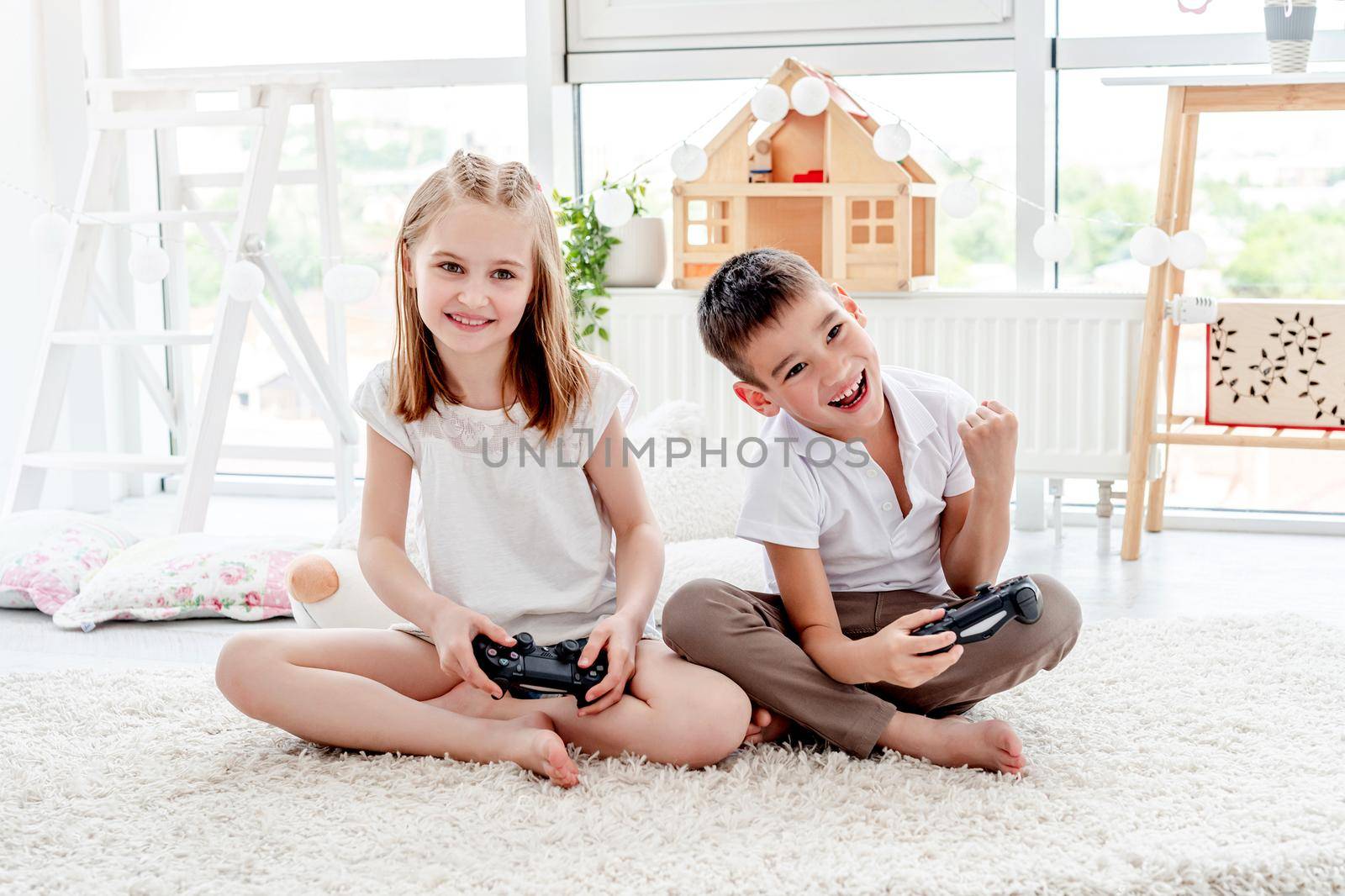 Little girl and boy playing on console by tan4ikk1
