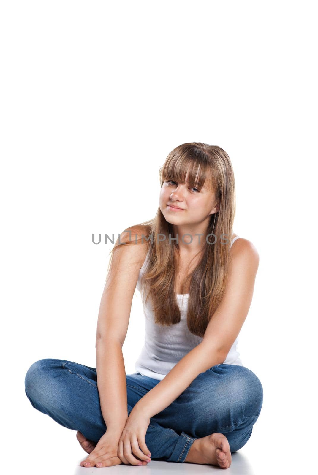 Smiling teenager girl sitting in studio on white background