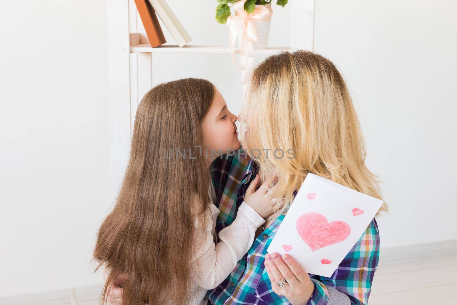 Happy mother's day. Child daughter congratulates mom and gives her postcard. Mum and kid girl smiling and hugging. Family holiday and motherhood. by Satura86