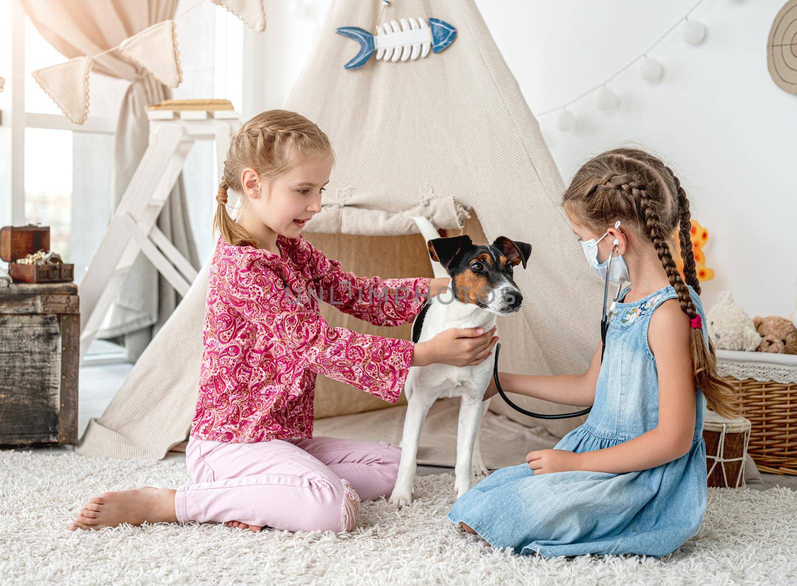 Little girls with phonendoscope listening dog like doctor sitting on floor in playroom