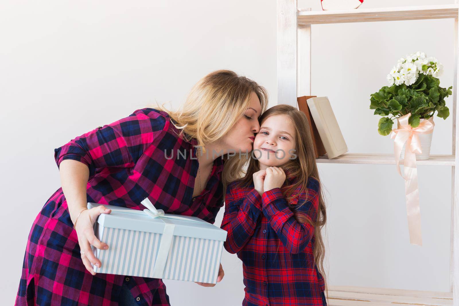 Adorable child girl with big gift box giving it to her mother. Holidays, birthday and presents.
