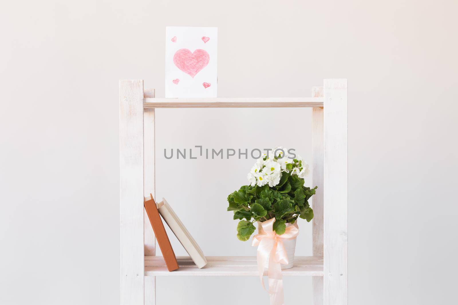 Picture of heart and books and indoor plant on a bookshelf. Minimal composition. Spring interior and moter's day concept. by Satura86