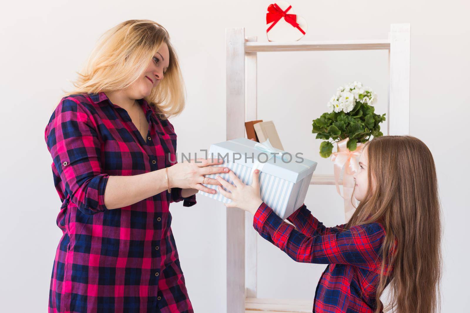 Young mother received a surprise from her daughter feeling excited open the mouth and looking at the gift in amazement in mother's day. Holidays, birthday and presents concept