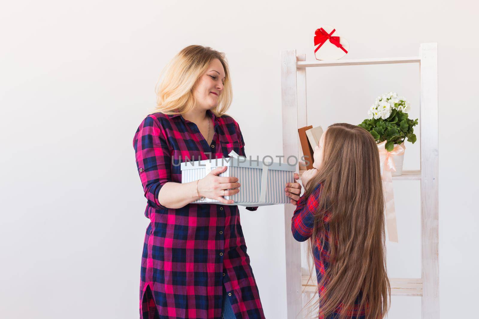 Young mother received a surprise from her daughter feeling excited open the mouth and looking at the gift in amazement in mother's day. Holidays, birthday and presents concept. by Satura86