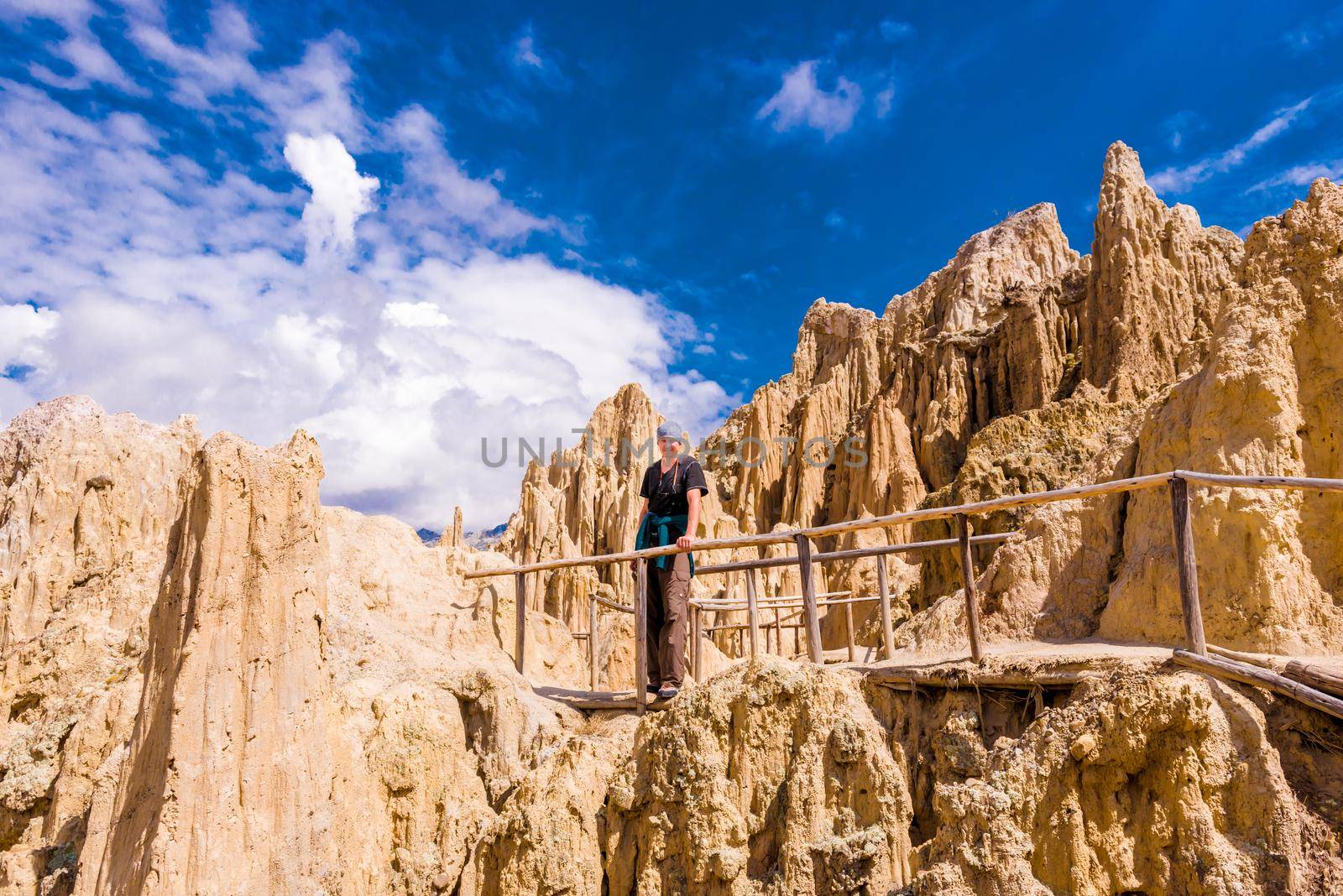 Tourist man standing at wooden mountain pathway at majestic Moon Valley, Bolivia