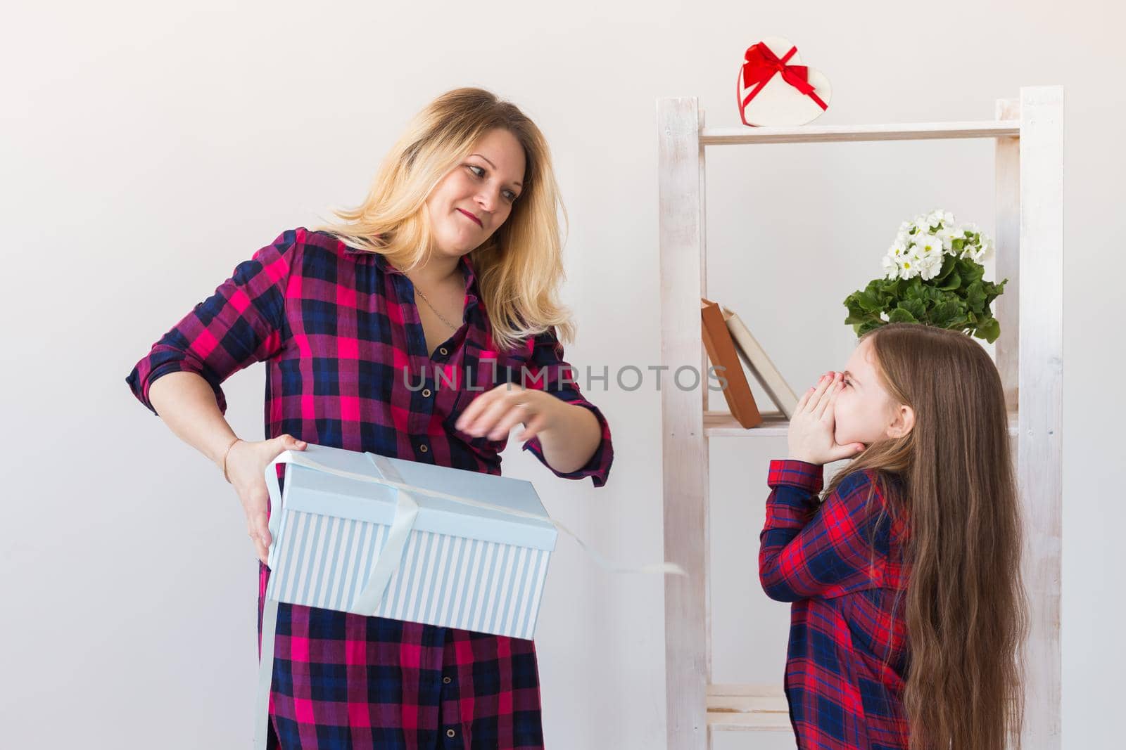 Adorable child girl with big gift box giving it to her mother. She is opens present. Holidays, birthday and presents.