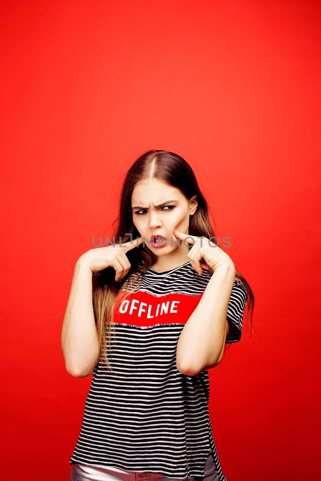 young pretty emitonal posing teenage girl on bright red background, happy smiling lifestyle people concept close up