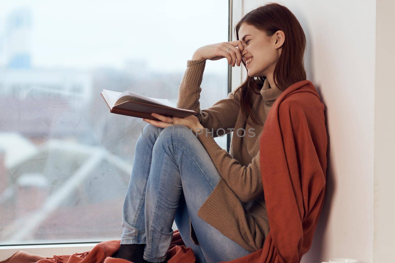 woman with a book near the window with a cup of coffee by Vichizh