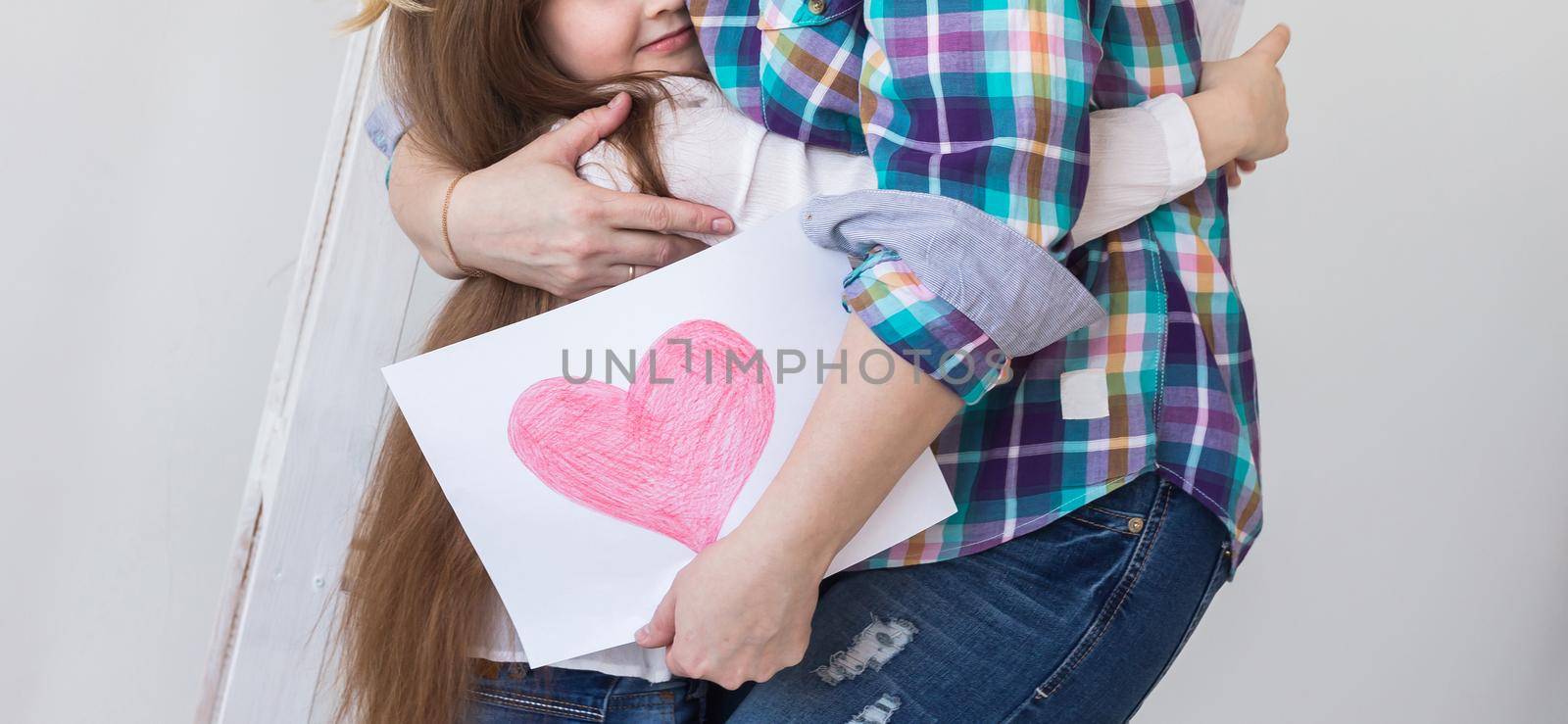 Happy mother's day. Child daughter congratulates mom and gives her postcard. Mum and kid girl smiling and hugging. Family holiday and motherhood. by Satura86