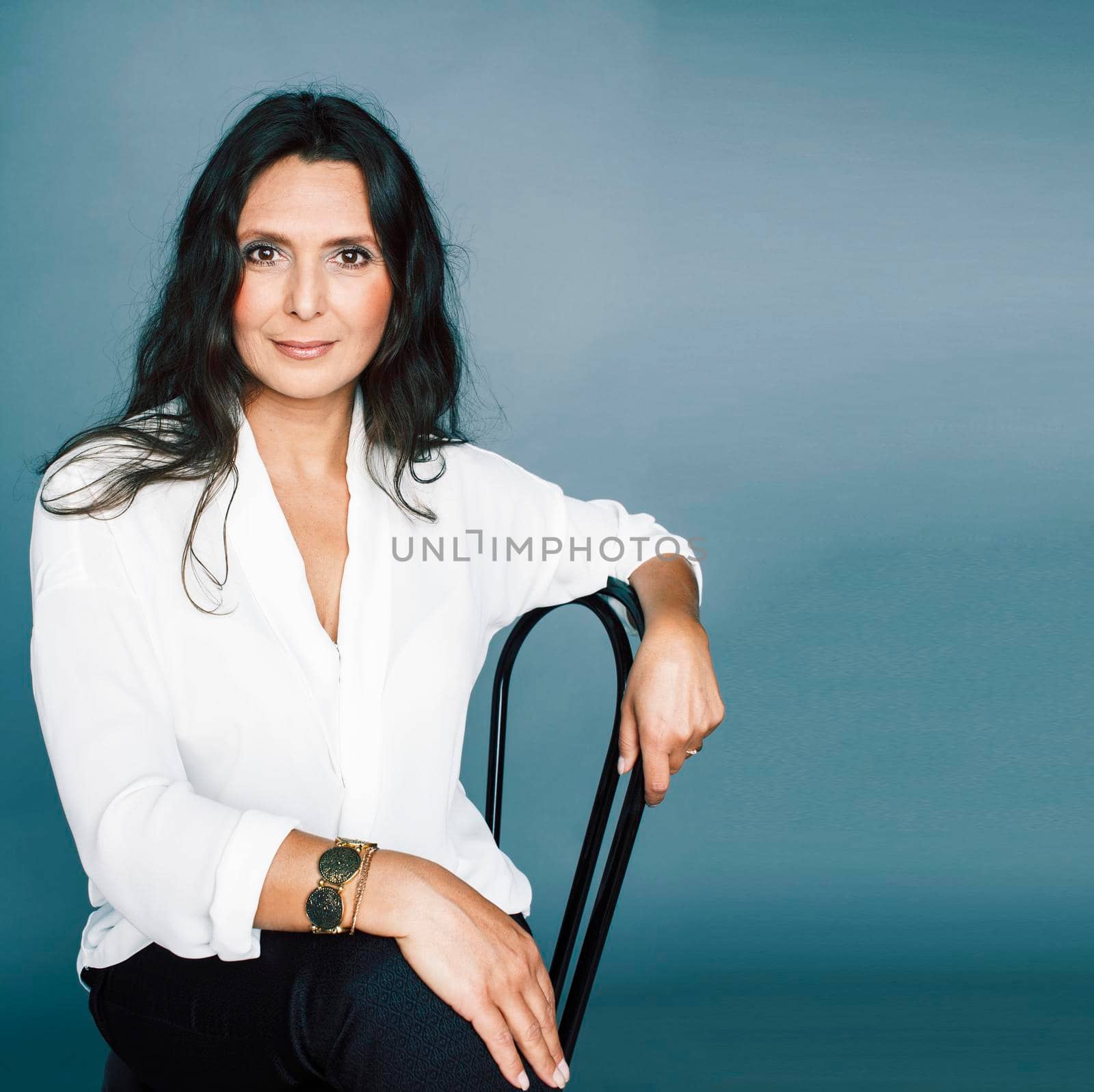 pretty brunette confident mature woman sitting on chair in studio, lifestyle people concept close up