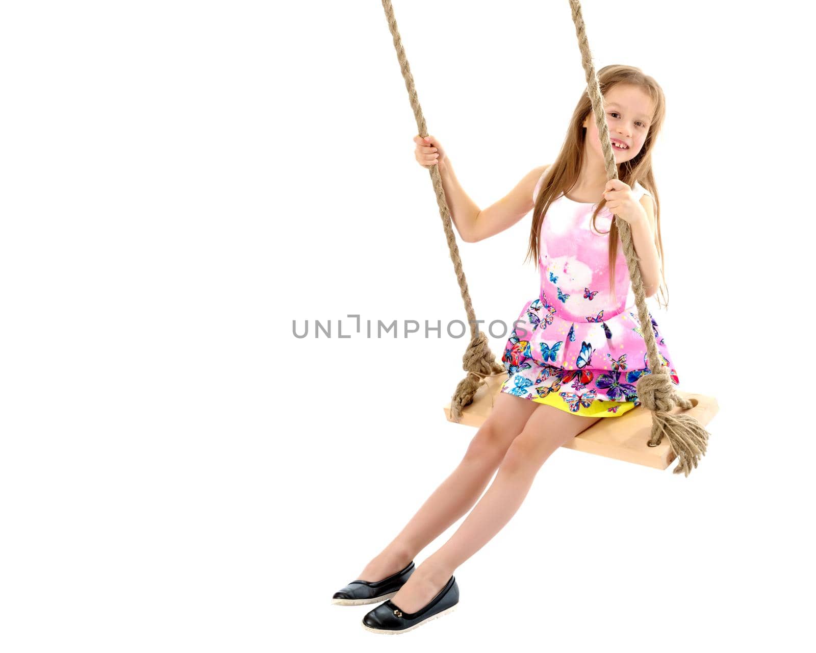 Adorable little girl swinging on a swing. She is happy to have fun and show how she can do it. The concept of summer recreation and harmonious development of the child. Isolated on white