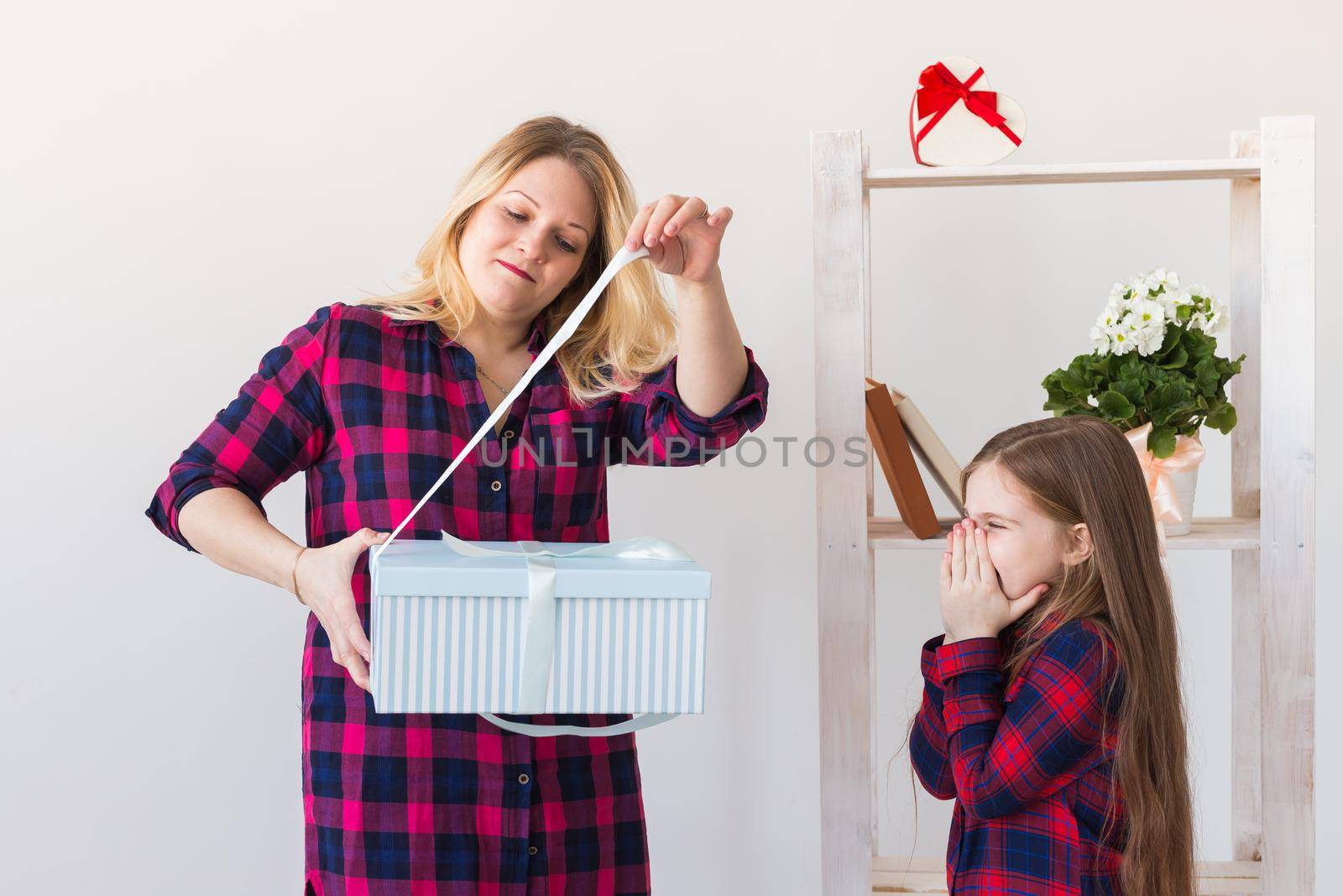 Young mother received a surprise from her daughter feeling excited open the mouth and looking at the gift in amazement in mother's day. Holidays, birthday and presents concept