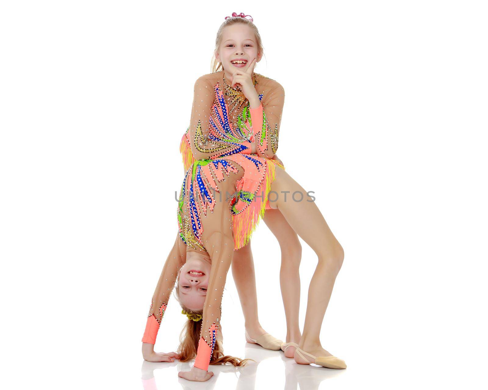 Two little twin girls who are doing gymnastics, doing the bridge.Isolated on white background.