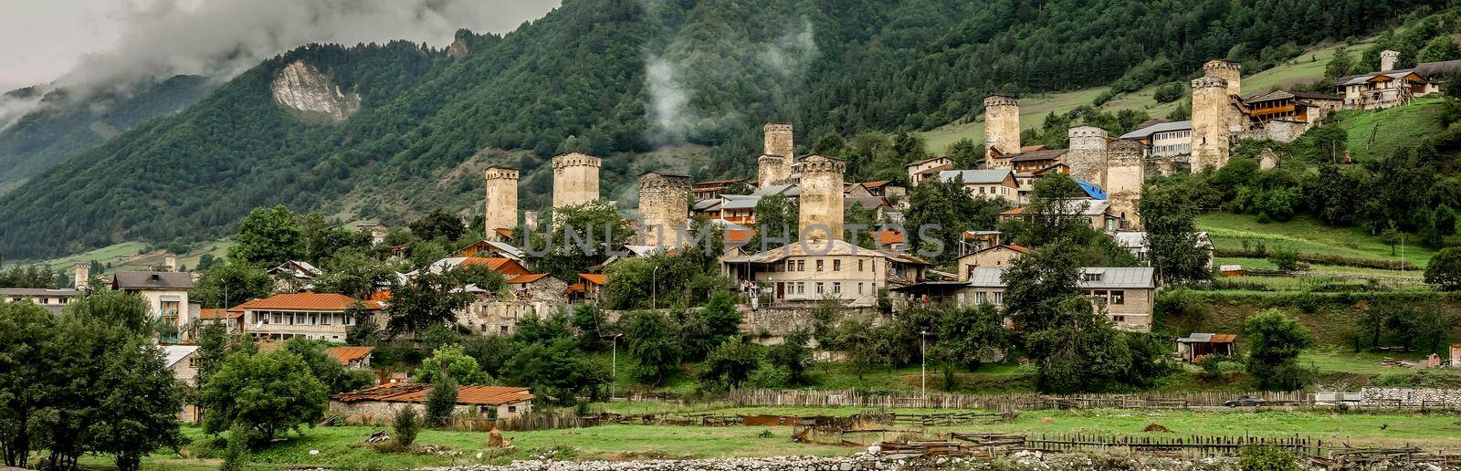 Pamorama of picturesque Mestia village in Svaneti region, Georgia. Green dense forest and mountaons covered with fog