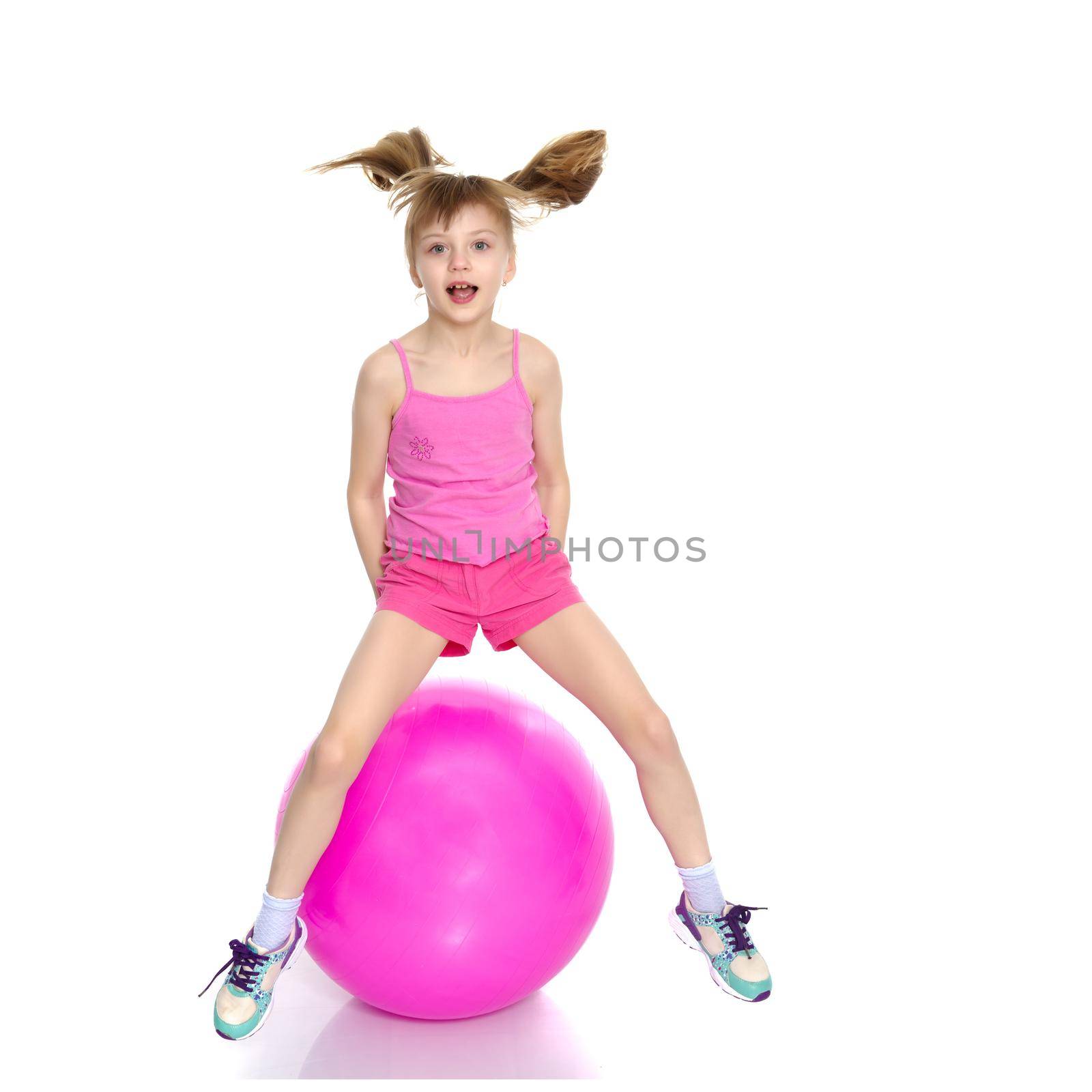 A little girl is jumping on a big ball for fitness. The concept of sport and a healthy lifestyle. Isolated on white background.