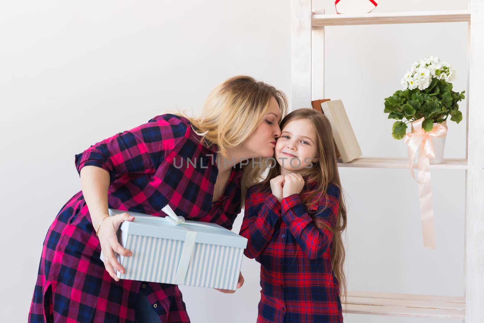 Young mother received a surprise from her daughter feeling excited open the mouth and looking at the gift in amazement in mother's day. Holidays, birthday and presents concept