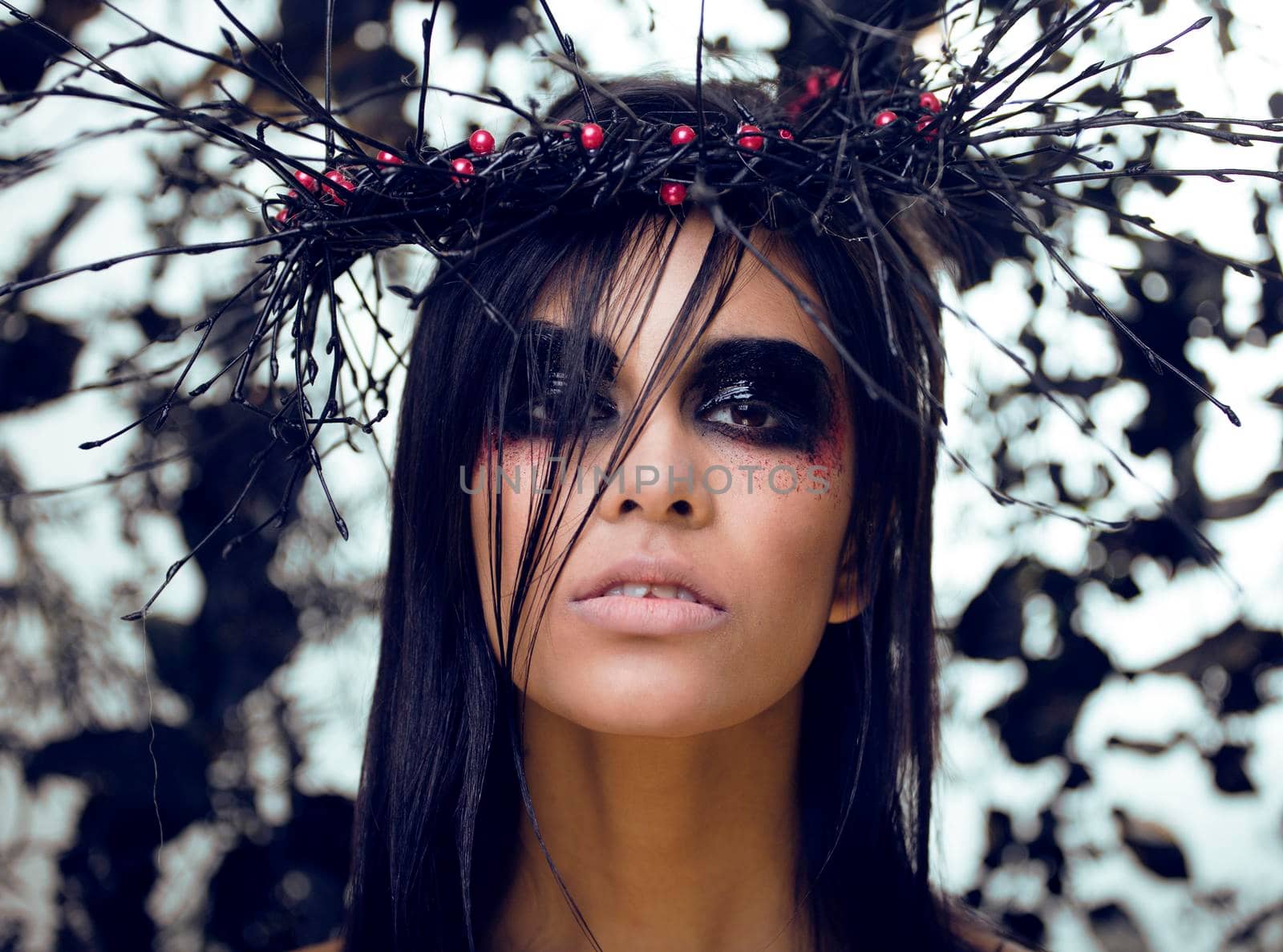 pretty brunette woman with make up like demon at halloween, closeup scary background