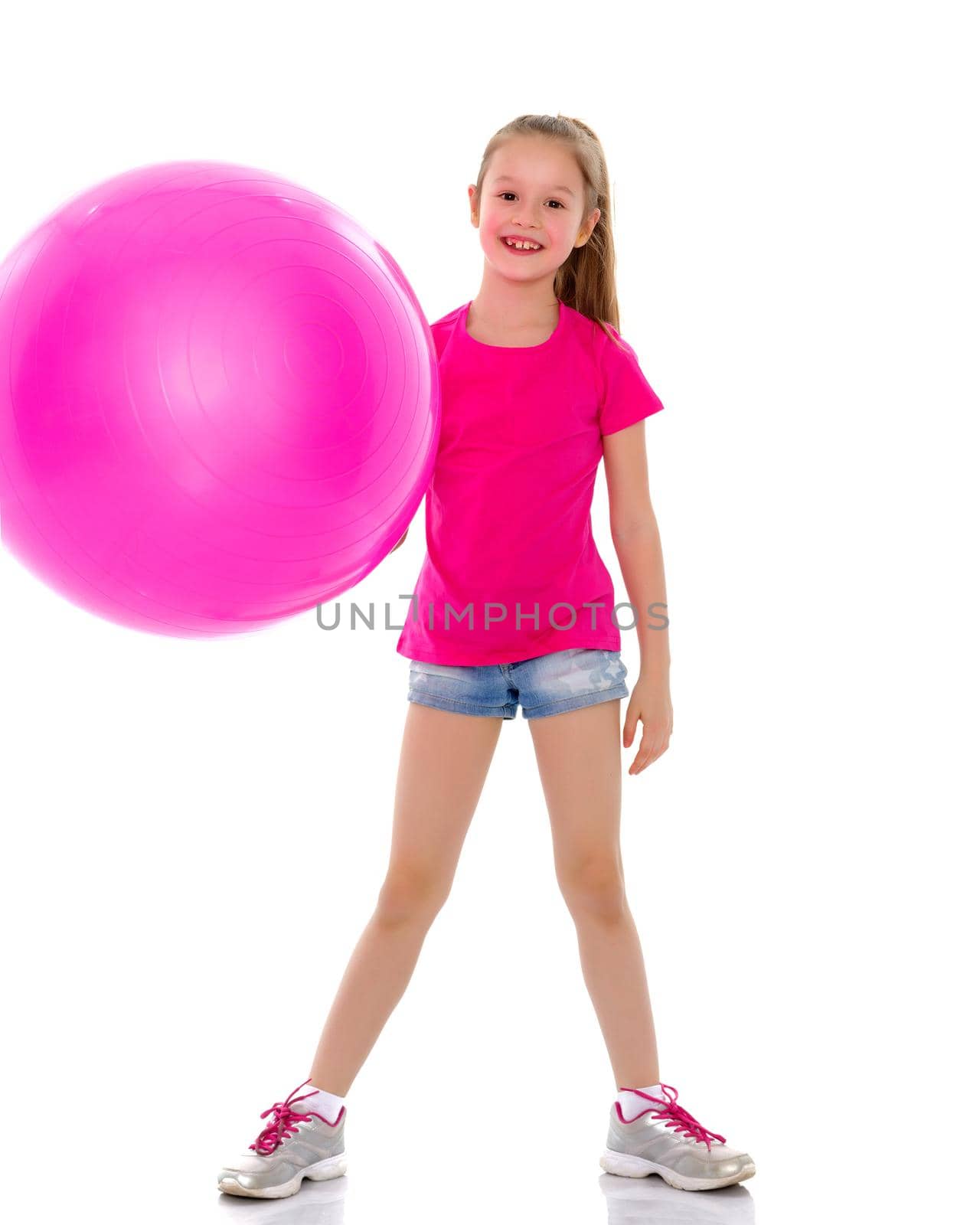 Beautiful little girl doing exercises on a big ball for fitness. The concept of sport and a healthy lifestyle. Isolated on white background.