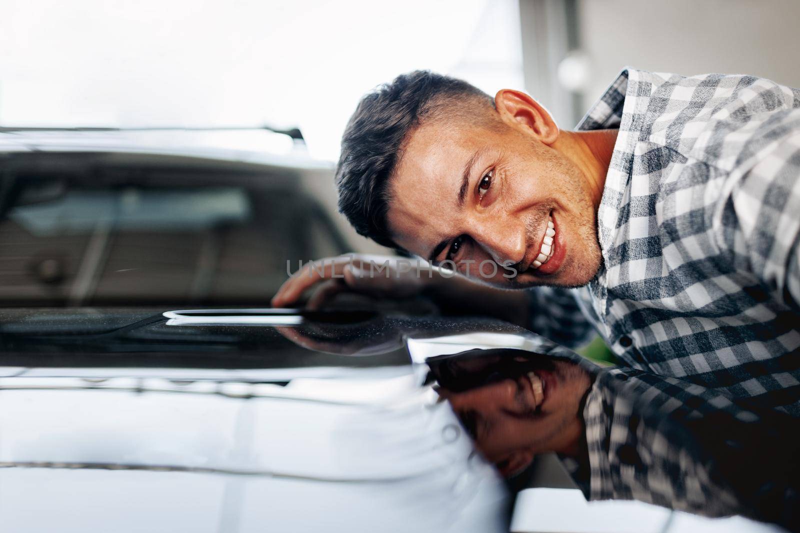 Cheerful young man customer buys a new car in a car dealership