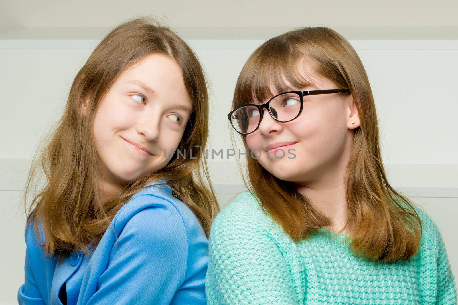 Two cute little girls close-up, in the studio on a white background. The concept of a happy childhood, Beauty and fashion. Isolated.