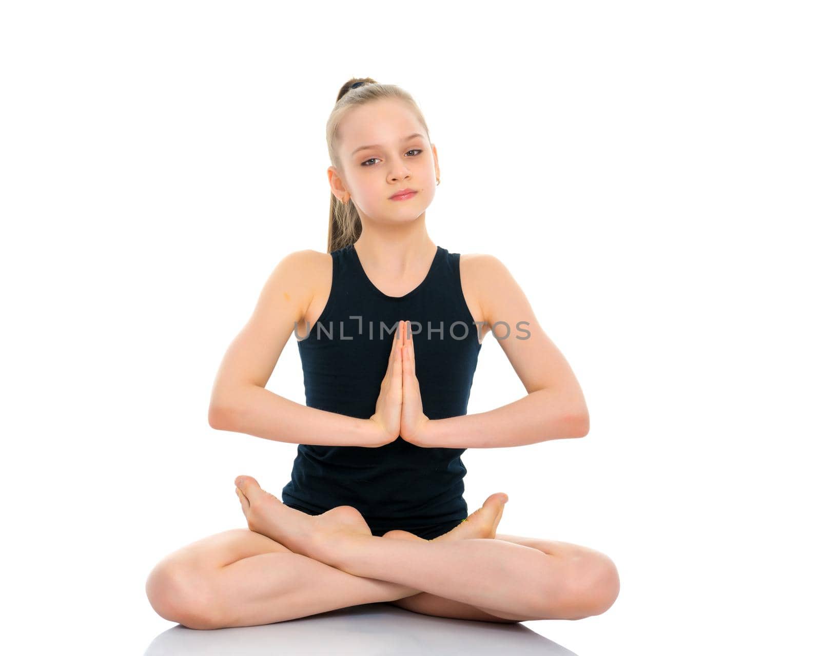 A nice little girl sits in a lotus position and meditates. Concept of yoga, happy people. Isolated on white background.