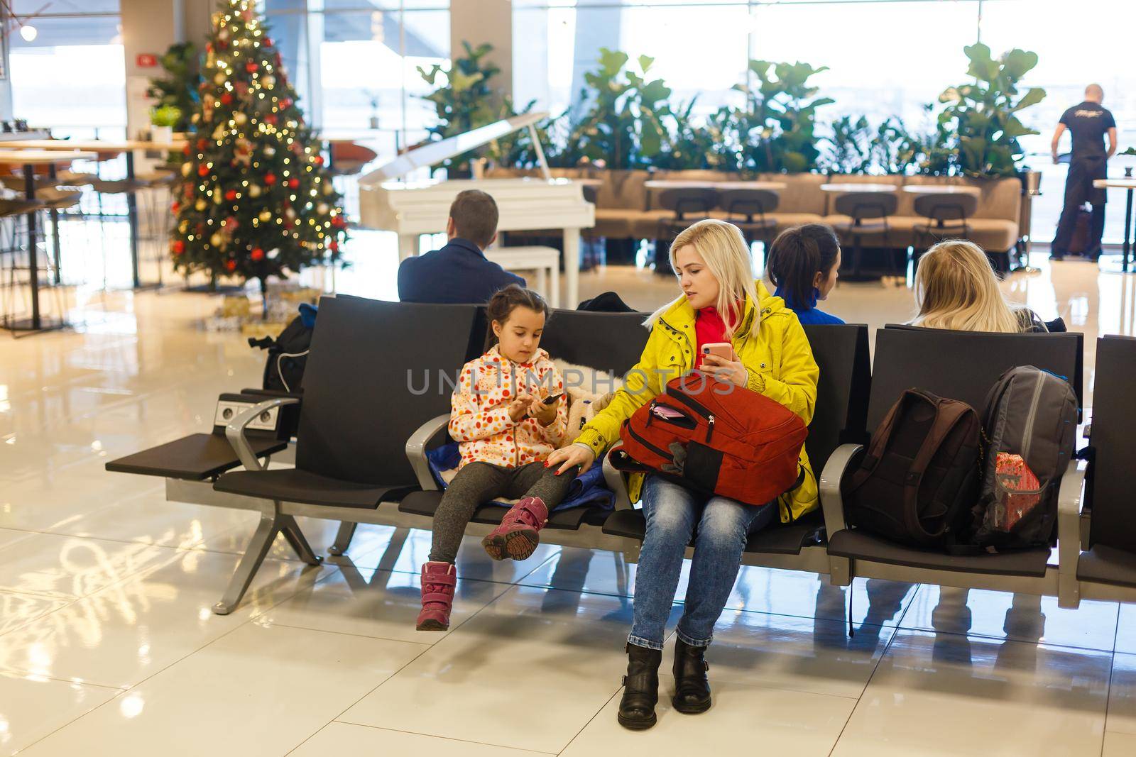 happy young mother playing a game with daughter at airport while waiting for their flight