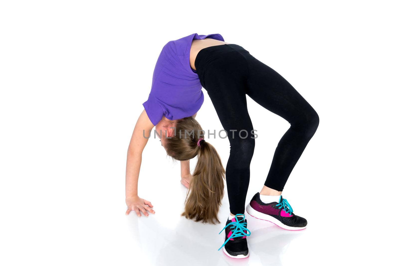 A little girl gymnast performs a bridge. The concept of childhood, sport, healthy lifestyle. Isolated on white background.