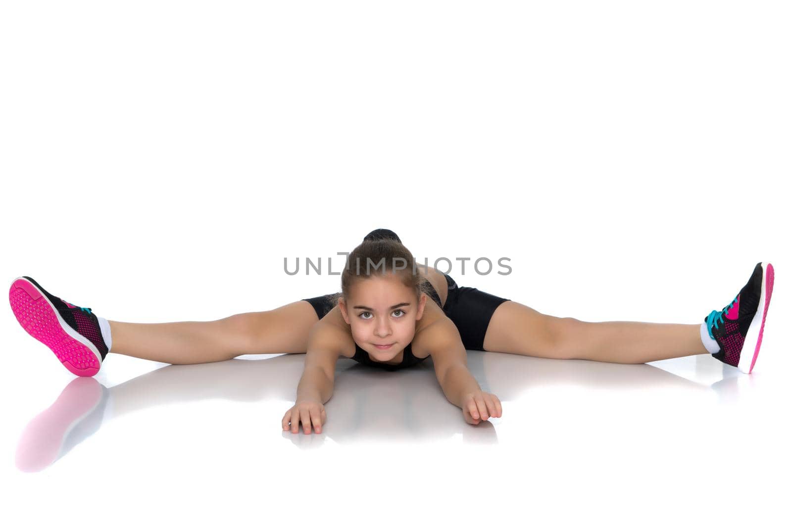 A little girl performs a gymnastic twine. The concept of fitness and sports. Isolated on white background.