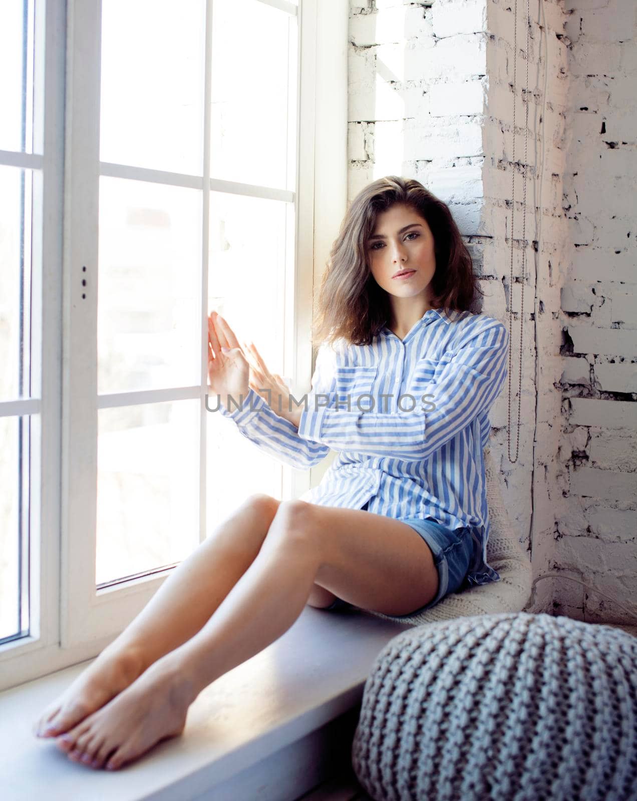 young pretty brunette woman in her bedroom sitting at window. lifestyle people concept by JordanJ