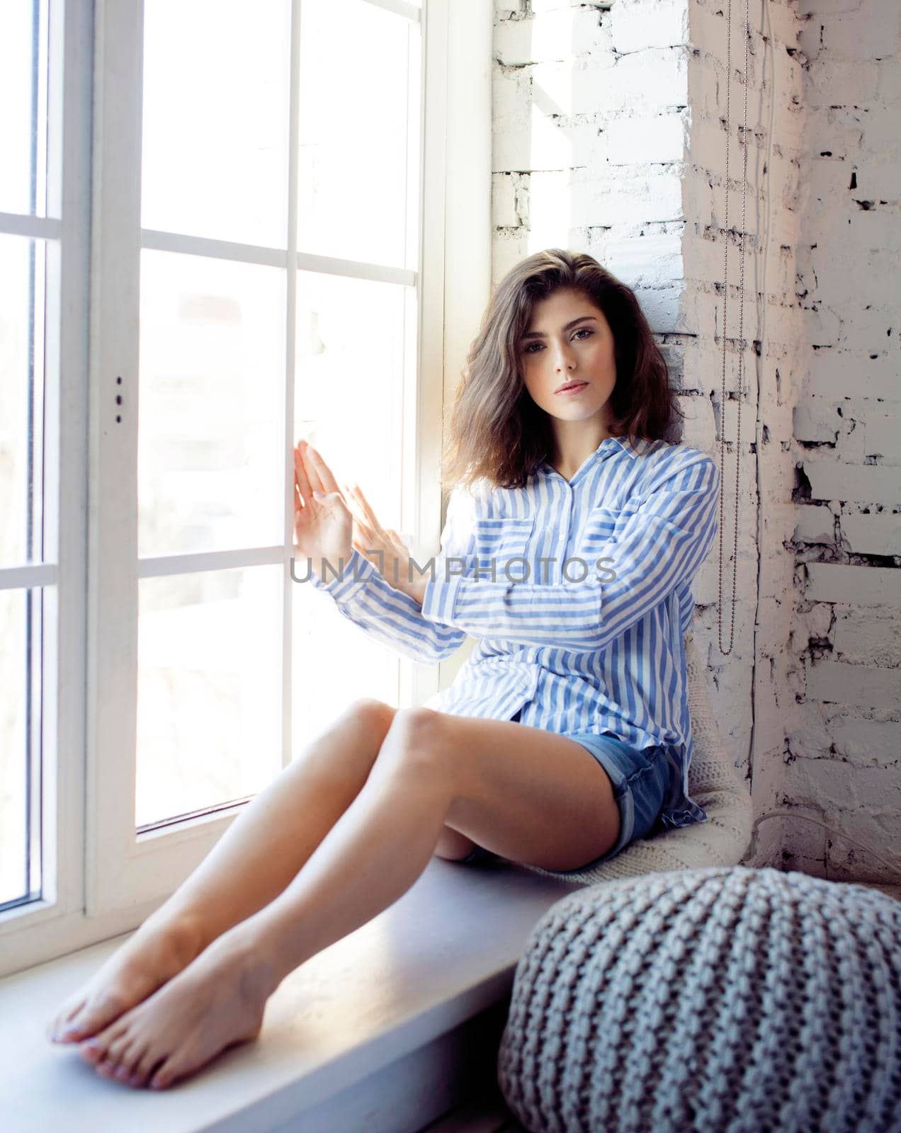 young pretty brunette woman in her bedroom sitting at window. lifestyle people concept